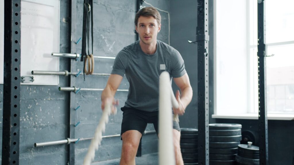 Man exercising with battle ropes in gym