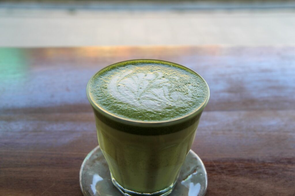 green liquid in clear drinking glass on white ceramic saucer